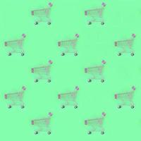 Shopping addiction, shopping lover or shopaholic concept. Many small empty shopping carts perform a pattern on a pastel colored paper background. Flat lay composition, top view photo