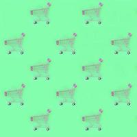 Shopping addiction, shopping lover or shopaholic concept. Many small empty shopping carts perform a pattern on a pastel colored paper background. Flat lay composition, top view photo