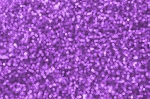 Blurred purple decorative sequins. Background image with shiny bokeh lights from small elements photo