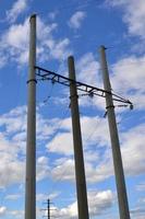 Concrete pole with wires of power line against the background of blue cloudy sky photo