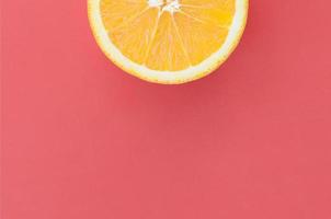 Top view of a one orange fruit slice on bright background in red color. A saturated citrus texture image photo