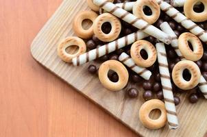 túbulos crujientes, bolas de chocolate y bagels yacen sobre una superficie de madera. mezcla de varios dulces foto