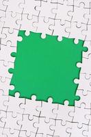 Framing in the form of a rectangle, made of a white jigsaw puzzle around the green space photo