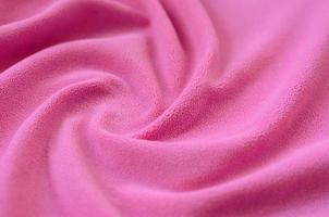 The blanket of furry pink fleece fabric. A background of light pink soft plush fleece material with a lot of relief folds photo