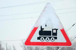 Railway crossing without barrier. A road sign depicting an old black locomotive, located in a red triangle photo