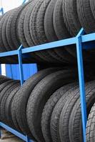 Rack with variety of car tires in automobile store. Many black tires. Tire stack background. Selective focus photo