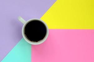 Small white coffee cup on texture background of fashion pastel blue, yellow, violet and pink colors paper in minimal concept photo