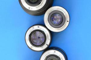 Several photographic lenses lie on a bright blue background. Space for text photo