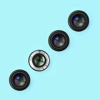 A few camera lenses with a closed aperture lie on texture background of fashion pastel blue color paper photo