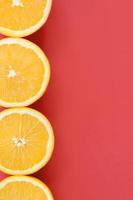 Top view of a several orange fruit slices on bright background in red color. A saturated citrus texture image photo