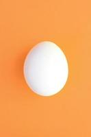 One white easter egg on a bright orange background photo