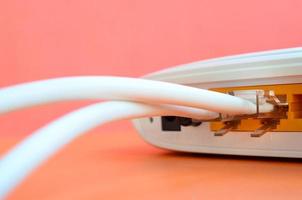 The Internet cable plugs are connected to the Internet router, which lies on a bright orange background. Items required for Internet connection photo