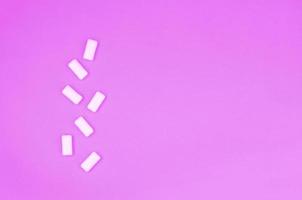 A few chewing gums lie on texture background of fashion pastel purple color paper photo