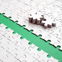 The green path is laid on the platform of a white folded jigsaw puzzle. The missing elements of the puzzle are stacked nearby. Texture image with space for text photo