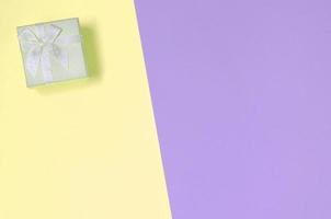 Small yellow gift box lie on texture background of fashion pastel yellow and violet colors photo