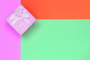 Small pink gift box lie on texture background of fashion pastel turquoise, red and pink colors paper photo