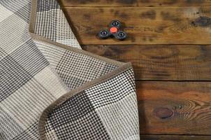 A rare wooden handmade spinner lies on a checkered plaid on a brown wooden background surface. Trendy stress relieving toy photo