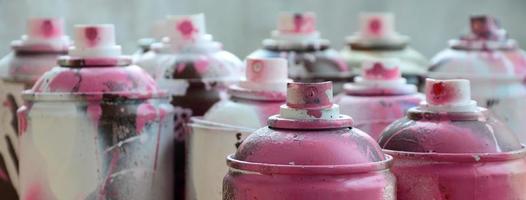 A lot of dirty and used aerosol cans of bright pink paint. Macro photograph with shallow depth of field. Selective focus on the spray nozzle photo