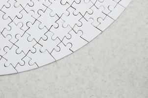 A white jigsaw puzzle in the complete form lies on a treated stone surface. Textured image with copy space photo