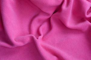 The blanket of furry pink fleece fabric. A background of light pink soft plush fleece material with a lot of relief folds photo