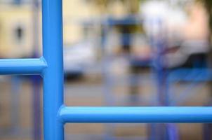 Blue metal pipes and cross-bars against a street sports field for training in athletics. Outdoor athletic gym equipment. Macro photo with selective focus and extremely blurred background