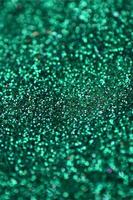 A huge amount of green decorative sequins. Background texture with shiny, small elements that reflect light in a random order. Glitter texture photo