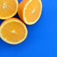 Top view of a several orange fruit slices on bright background in blue color. A saturated citrus texture image photo