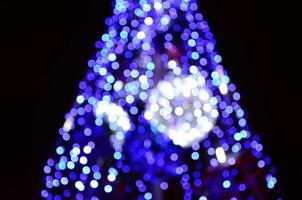 Blurred fragment of the New Year tree. Lots of round lights in blue photo