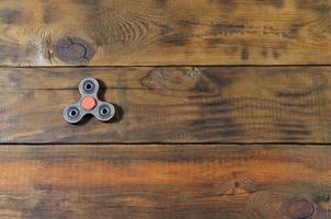 A rare handmade wooden fidget spinner lies on a brown wooden background surface. Trendy stress relieving toy photo