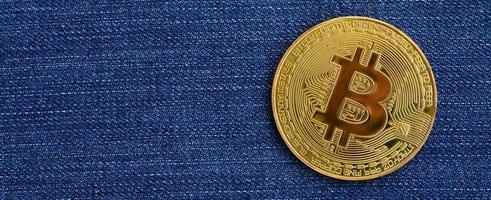 bitcoin dorado yace sobre una tela de jeans azules. nuevo dinero virtual. nueva moneda criptográfica en forma de monedas foto