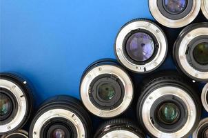 Several photographic lenses lie on a bright blue background. Space for text photo