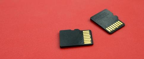 Two small micro SD memory cards lie on a red background. A small and compact data and information store photo