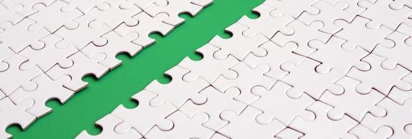 The green path is laid on the platform of a white folded jigsaw puzzle. Texture image with copy space for text photo