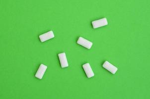 A few chewing gums lie on texture background of fashion pastel green color paper in minimal concept photo