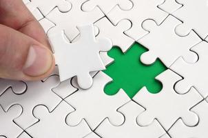 The human hand fills the last missing elements of the surface from the jigsaw puzzle. The concept of the completion of the initiated cases photo
