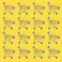 Shopping addiction, shopping lover or shopaholic concept. Many small empty shopping carts perform a pattern on a pastel colored paper background. Flat lay composition, top view photo