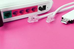 el enrutador de Internet, el adaptador wi-fi usb portátil y los enchufes de cable de Internet se encuentran sobre un fondo rosa brillante. elementos necesarios para internet foto