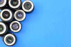 Several photographic lenses lie on a bright blue background. Space for text photo