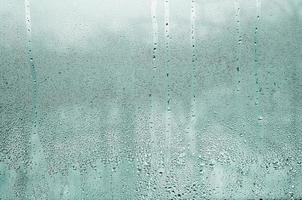 Texture of a drop of rain on a glass wet transparent background. Toned in turquoise color photo