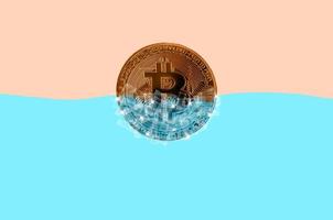 Frozen golden bitcoin in blocks of ice in blue water photo