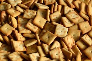 Background texture of small edible squares baked from dough and sprinkled with salt. A lot of salt cracker photo