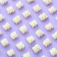 Colorful marshmallow laid out on violet paper background. pastel creative textured pattern. minimal photo