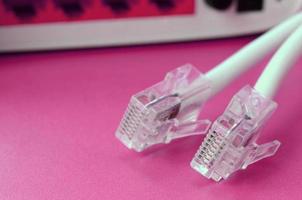 el enrutador de Internet y los enchufes del cable de Internet se encuentran sobre un fondo rosa brillante. elementos necesarios para internet foto