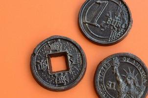 Three chocolate products in the form of Euro, USA and Japan coins lie on an orange plastic background. A model of cash coins in an edible form photo