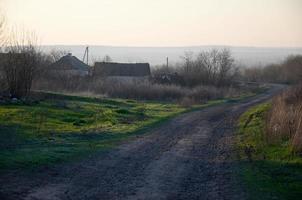 Dawn in the village. Asphalt road, leaving far into the distance among the fields photo