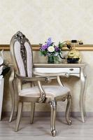 A fragment of a retro interior with a chair and a desk on which is located a telephone and a vase of flowers photo