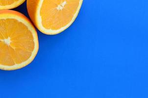 Top view of a several orange fruit slices on bright background in blue color. A saturated citrus texture image photo