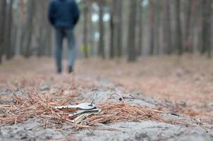 Young man loses his keys bunch on Russian autumn fir wood path. Carelessness and losing keys concept photo