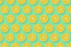 Pattern of yellow lemon citrus slices on bright green background photo