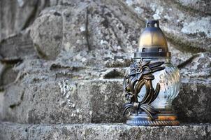 A metal lamp stands on the stone surface of an old crypt photo